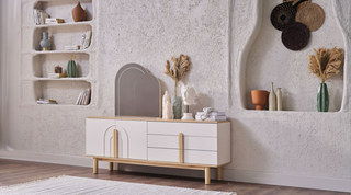 White console with wooden legs in a room with decorative elements on the wall.