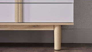 Close-up of a modern piece of furniture with wooden legs and glass top.