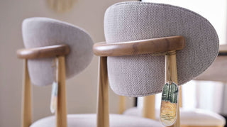 Two cushioned chairs with wooden legs in a room setting.