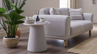 Gray sofa with a small round table and decorative items in a living room setting.