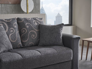 Gray sofa with patterned cushions in a room with a cityscape view through a window.