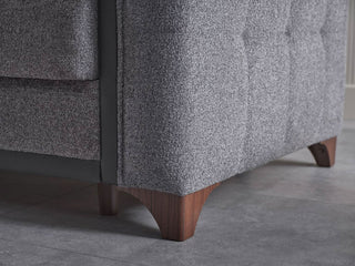 Gray upholstered chair with wooden legs on a gray floor.