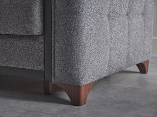 Gray upholstered chair with wooden legs on a gray floor.