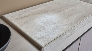 Close-up of a beige marble countertop with a bowl on the left side.