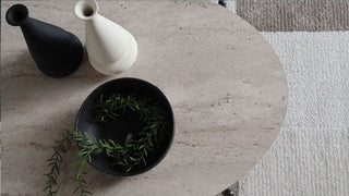 Decorative items including a black vase, white ceramic piece, and a black bowl with greenery on a textured surface