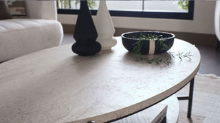 Round marble coffee table with decorative items in a living room setting