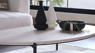 Round stone coffee table with decorative items in a living room setting