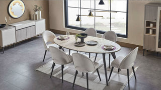 Modern dining room with a round table and chairs near a large window.